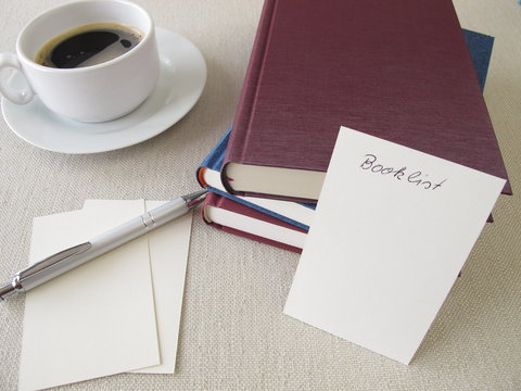 Book pile, blank booklist and cup of coffee