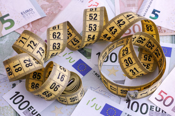 Euro banknotes and yellow tape measure