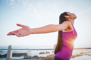 Carefree fit woman with arms outstretched at promenade