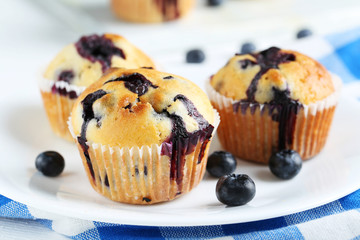 Tasty blueberry muffins on a white wooden background