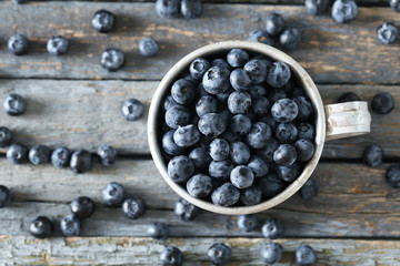 Blueberries in mug on a blue wooden background