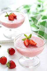 Tasty strawberry mousse in glass on white wooden table