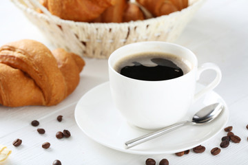 Delicious croissants with cup of coffee on white wooden backgrou