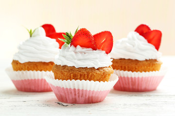 Tasty cupcake with strawberry on white wooden background