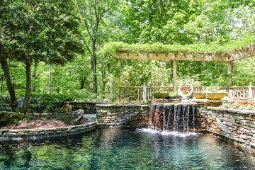 Fototapeta na wymiar Fountain and Stone Wall at a Garden Lake