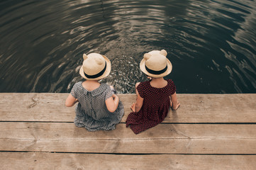 Young girl dipping feet in the lake from the edge of a wooden bo