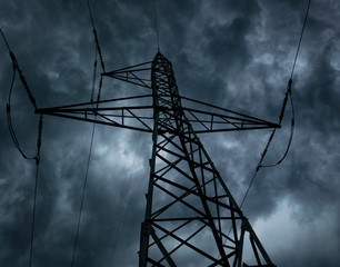 High voltage pole on dark, heavy clouds background, symbolising the negative impact of...