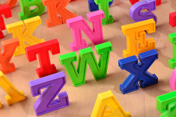 Fototapeta premium Plastic colorful letters close up on a wooden background