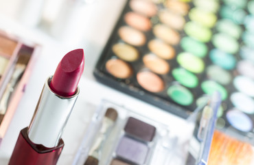 Red lipstick with blur cosmetics background such as makeup palette and blush on and negative space for word and text.