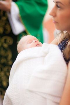 Mother hold baby on ceremony of child christening