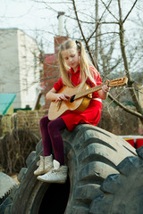 Obraz na płótnie Canvas girl playing guitar sitting on tires