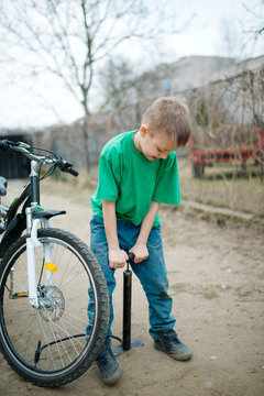 boy pumps up his bicycle wheel