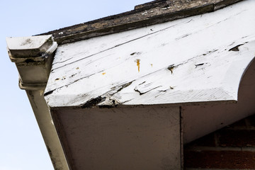 Peeling paint and rotting woodwork around house gutter and fasci