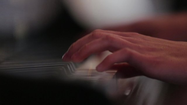 Woman playing piano at concert. Close up for hands and keys.
