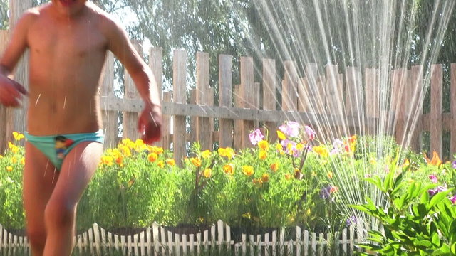 Little boy plays with sprinkler, in the garden
