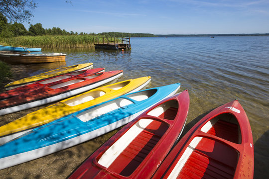 Colorful kayaks moored on lakeshore, Goldopiwo Lake, Mazury, Pol
