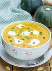 Pumpkin soup with sour cream on a wooden table