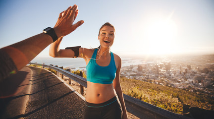 Fit young woman high fiving her boyfriend after a run