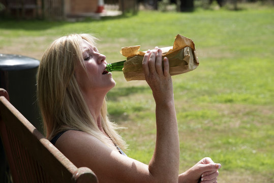 Woman Drinking Alcohol With Bottle In Brown Paper Bag In A Public Place