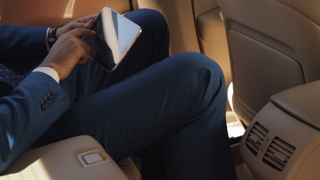 Businessman sitting in the car reading tablet
