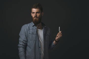 Portrait of bearded man with straight razor