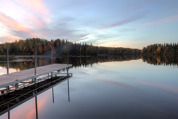 Pier on calm lake at sunset