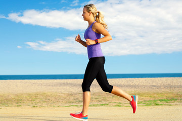 Young woman jogging along beach.