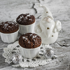 chocolate muffins and Christmas decoration ceramic Santa Claus on a light wooden surface, vintage style