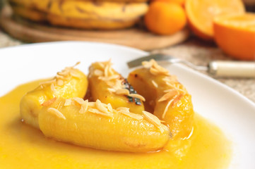 Bananas flambe with nuts on a white plate