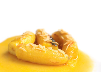 Bananas flambe with nuts on white background