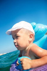 Close up od little smiling boy enjoying in the sea in inflatable rubber ring