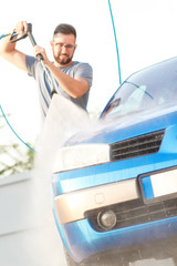 Fototapeta premium Man washing his car with using a high pressure water jet