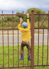 Obraz premium Boy on a fence. the boy climbed onto a high fence
