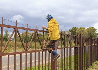 climb fence. Boy going to climb over the high fence