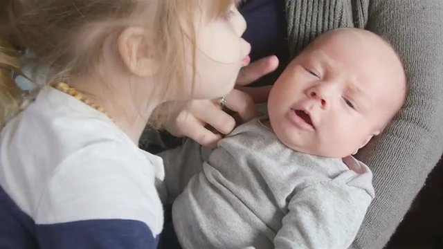 Newborn boy kissed by toddler sister