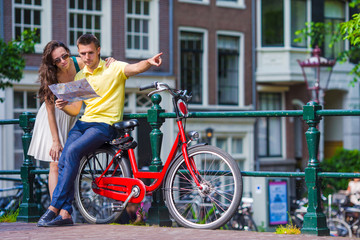 Fototapeta na wymiar Young tourists couple looking at map with bikes in european city