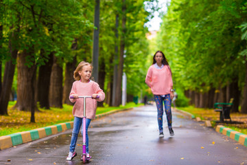 Fototapeta premium Adorable little girl with happy mom have fun on the scooter