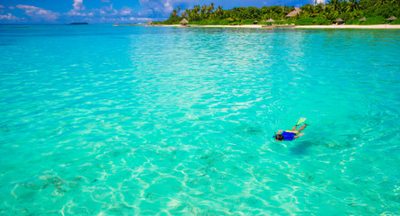 Young man snorkeling in clear tropical turquoise waters