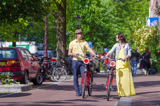 Young happy caucasian couple on bikes in old streets in