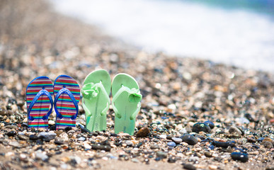 Kids colorful flip flops on beach in front of the Mediterranean