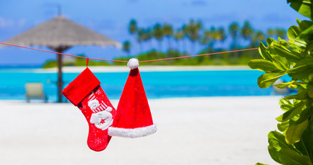 Fototapeta na wymiar Red Santa hat and Christmas stocking between palm trees