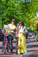 Fototapeta premium Young tourists couple looking at map with bikes in european city