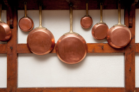 Vintage copper pans hung on wooden shelf