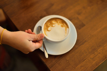 A cup of coffee with in white cup on wooden background.