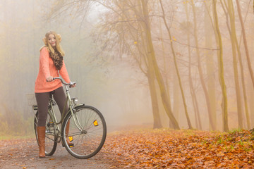 Obraz premium Active woman riding bike in autumn park.