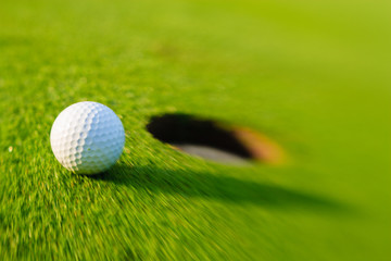 Golf ball dropping into the cup.