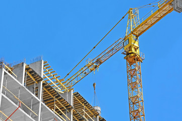 Crane and building construction site against blue sky