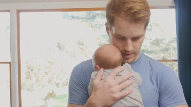 Father walking and bouncing newborn son in living room