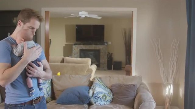 Father walking and bouncing newborn son in living room