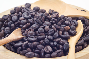 Coffee beans on a wooden plate and white background.
